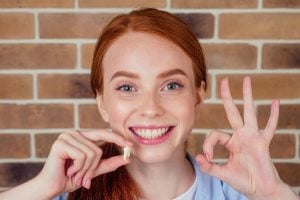 a woman holds an extracted wisdom tooth
