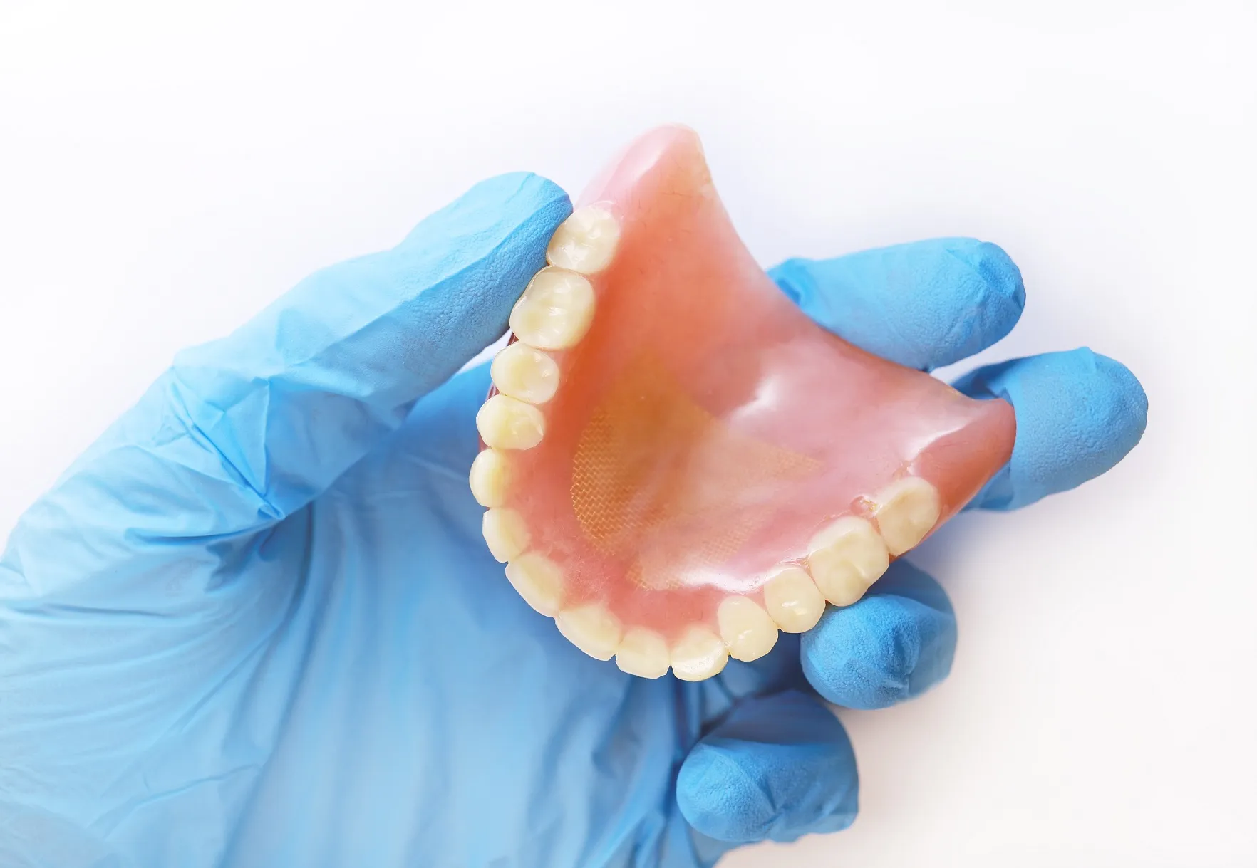 a gloved hand holds a denture